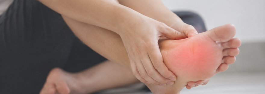 Person holding the bottom of their foot due to heel pain from plantar fasciitis